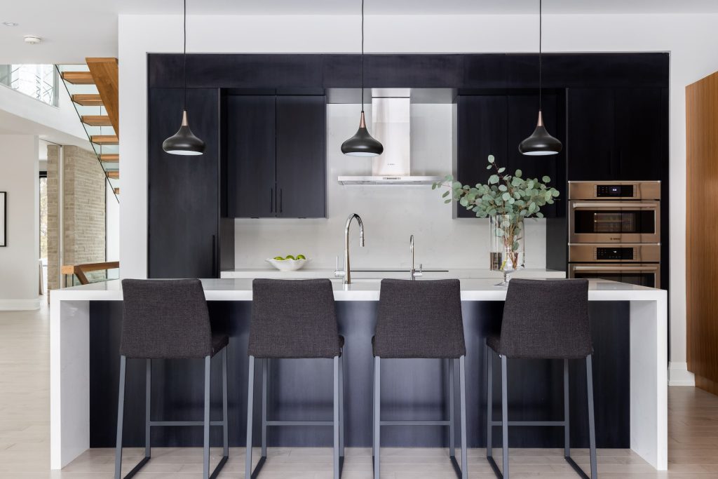 A kitchen with stools alongside the island