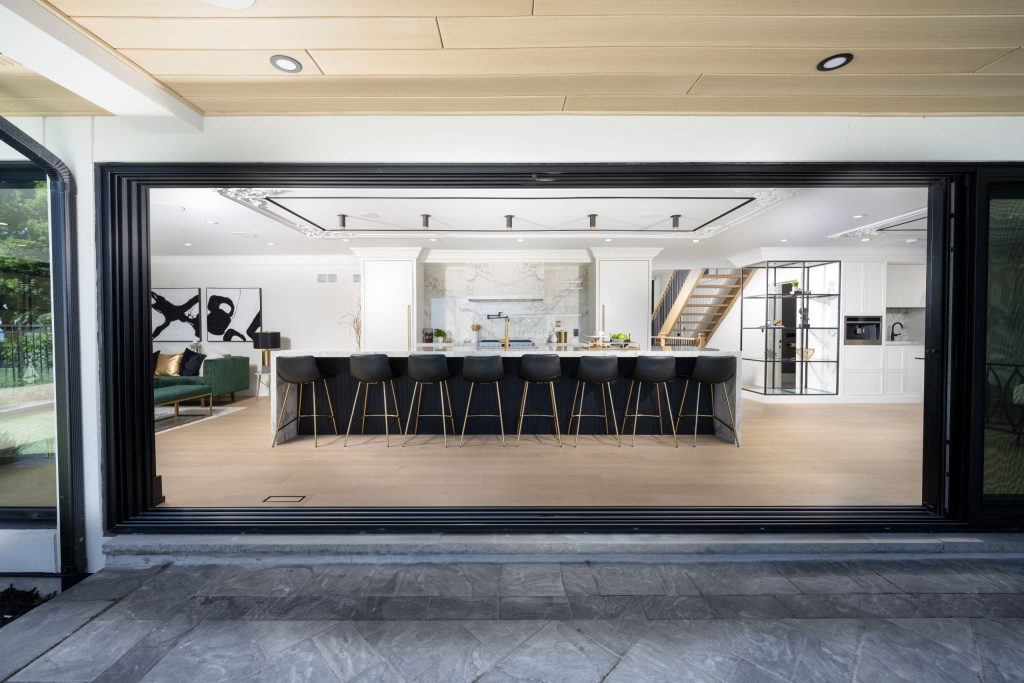 The view of an open kitchen from the backyard through a huge window/door,