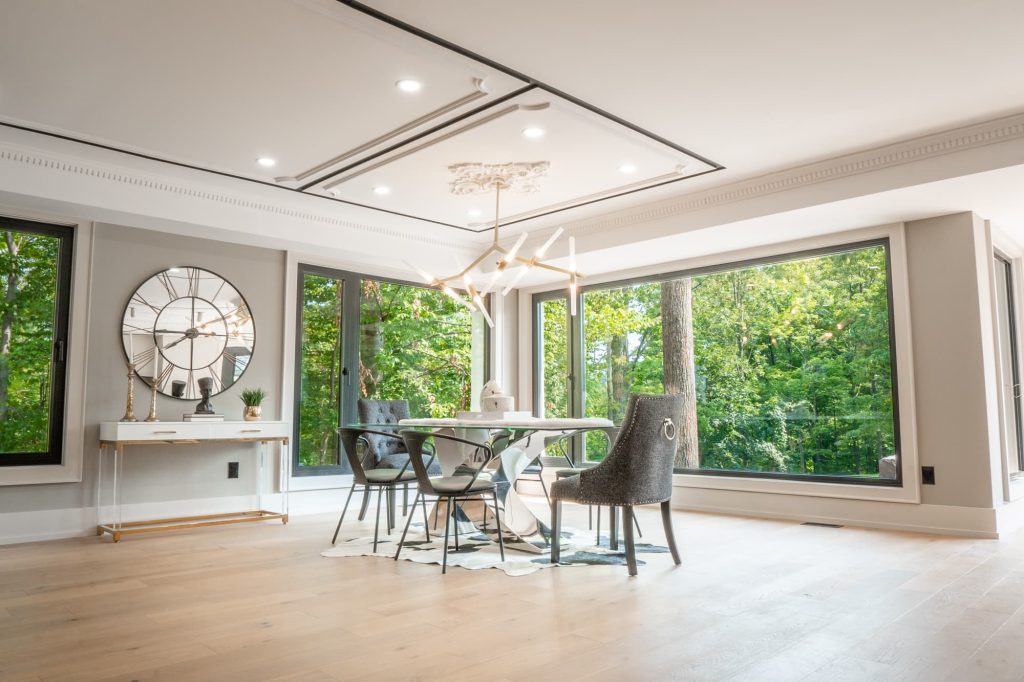 A dining room with large windows with a view of trees.