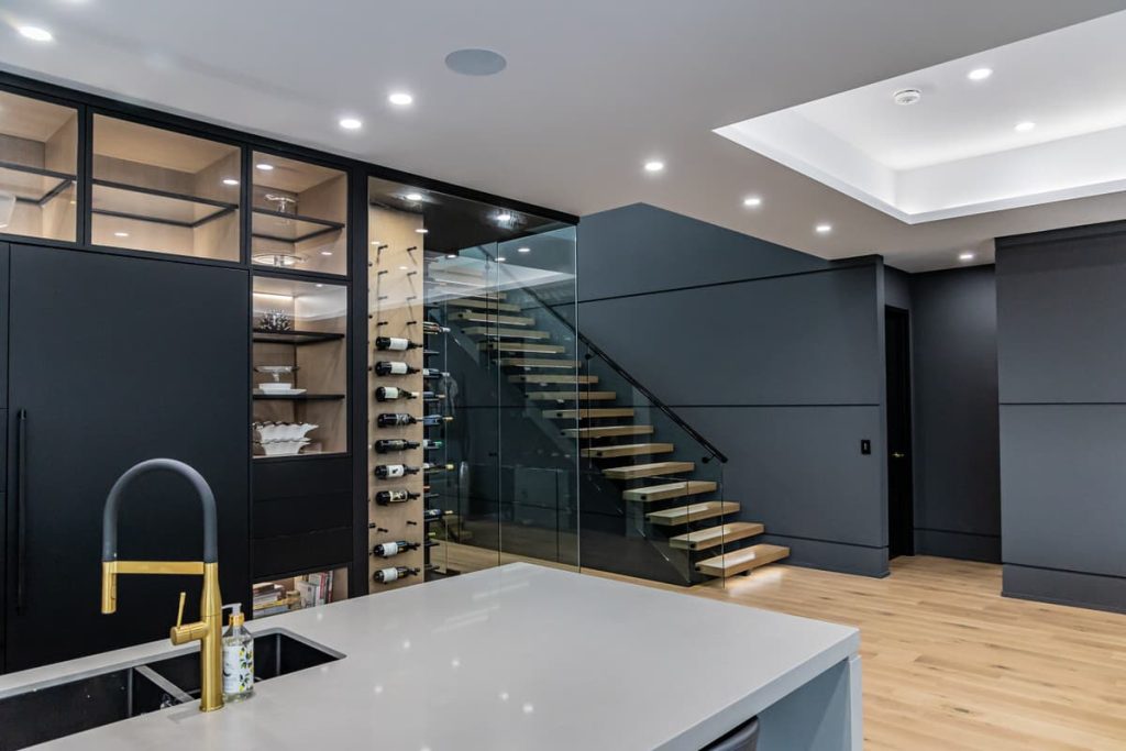 Looking towards a staircase past a wine cellar and a kitchen island